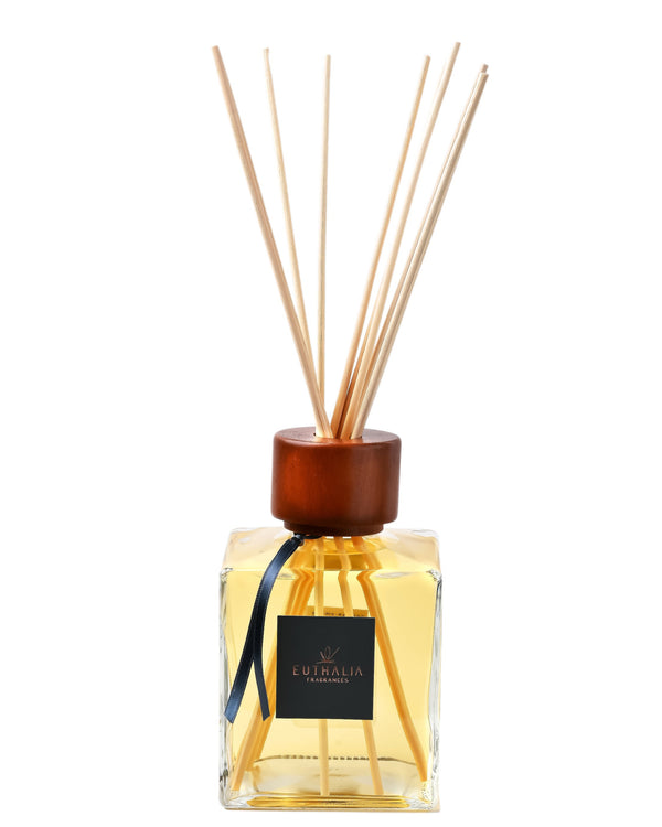 Reed diffuser with wooden cap and visible brand label on a white background