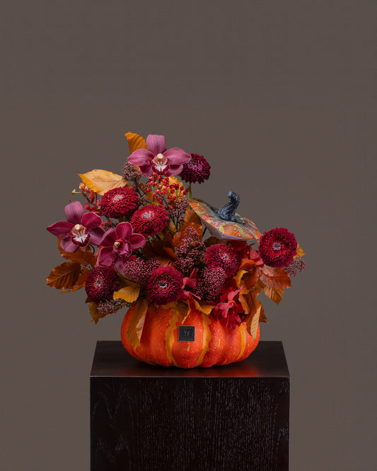 Monster Mash Flower Arrangement featuring burgundy cymbidium orchids and crimson blooms in a ceramic pumpkin centerpiece